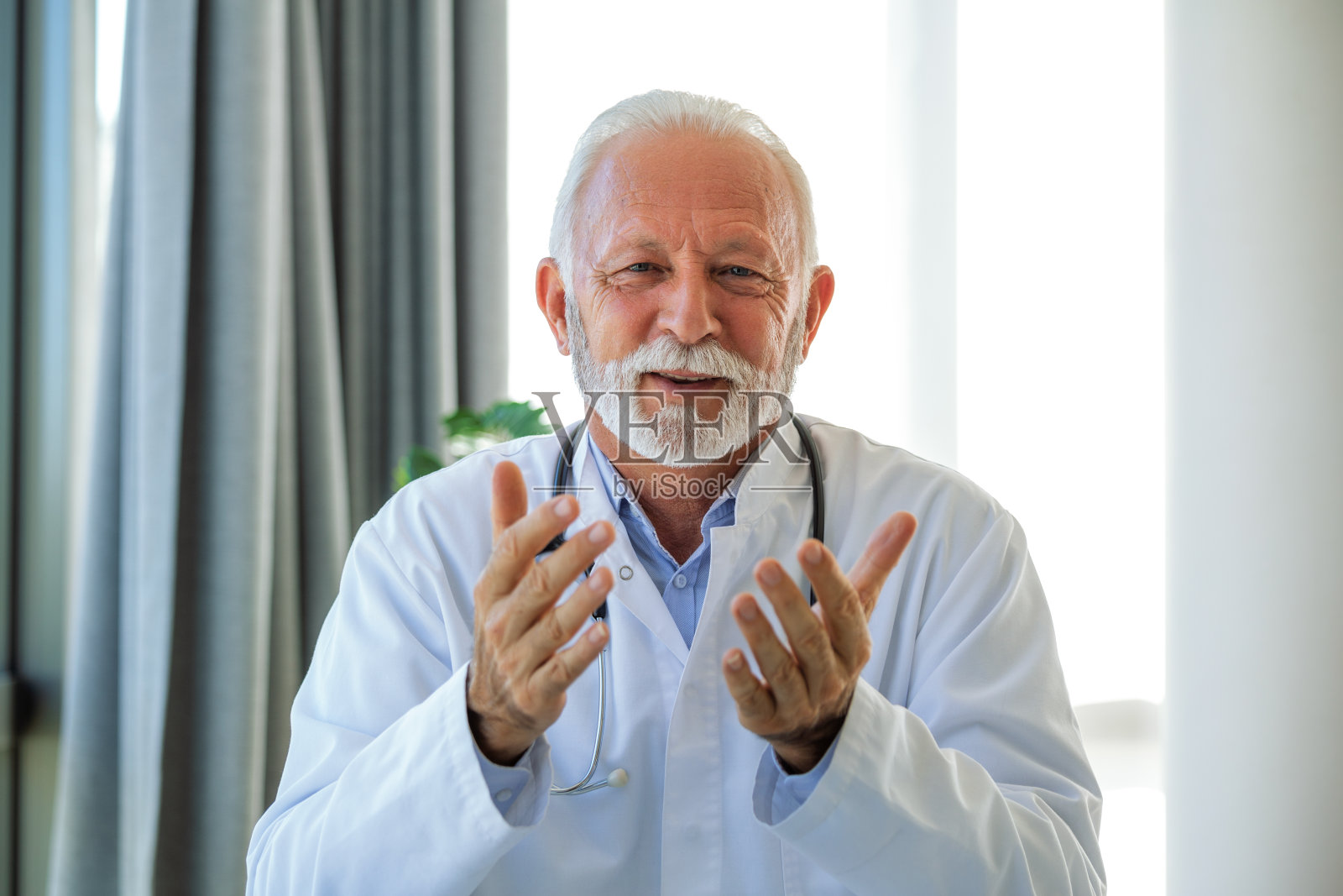 在线医生。高级医生在办公室用笔记本电脑和病人谈话。成熟的男性治疗师在会诊过程中通过笔记本电脑视频通话向患者讲解医疗。照片摄影图片