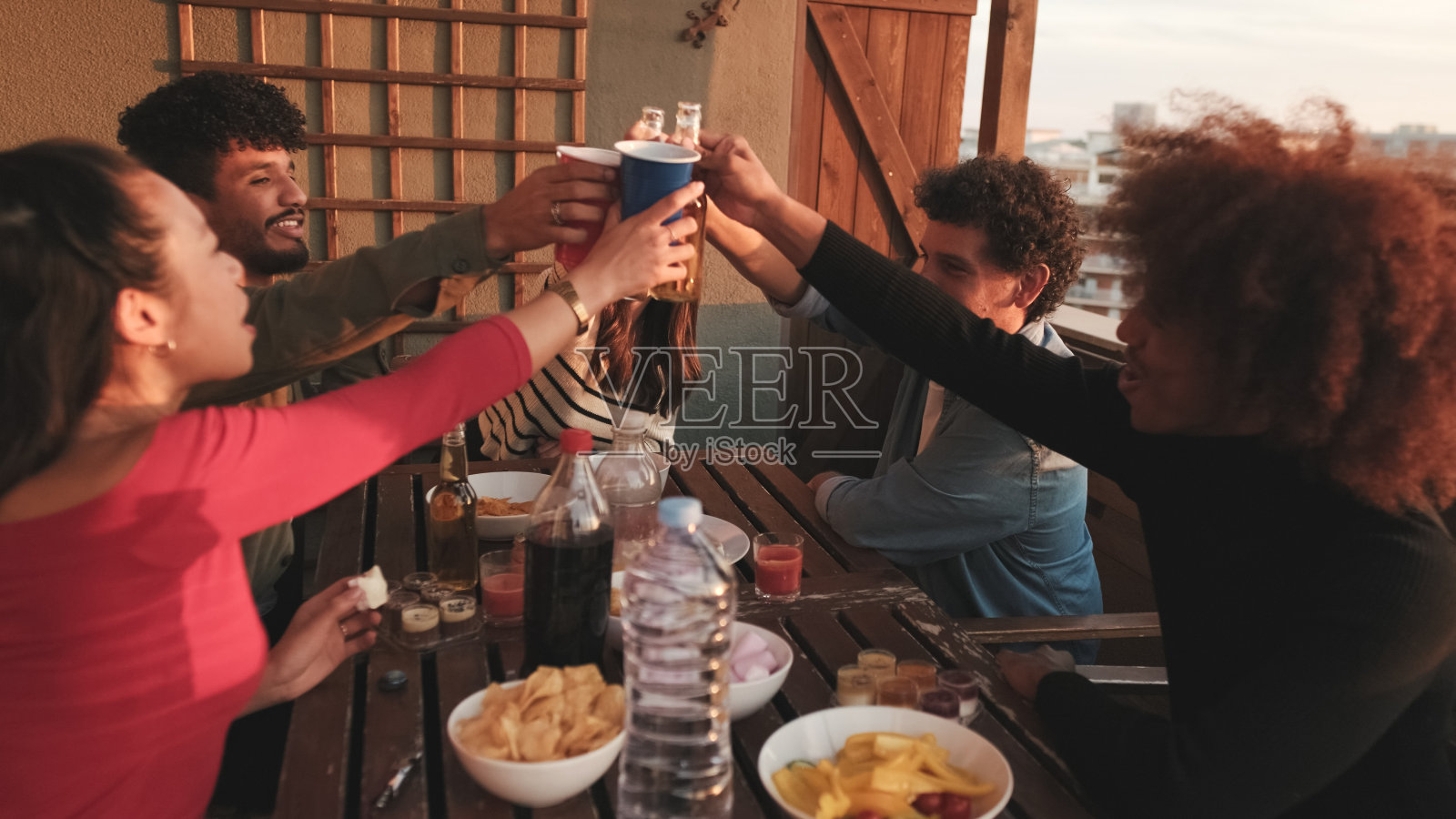 在露台上聚会的男孩和女孩吃和喝，有乐趣和开玩笑的桌子周围，友好的聚会假期照片摄影图片