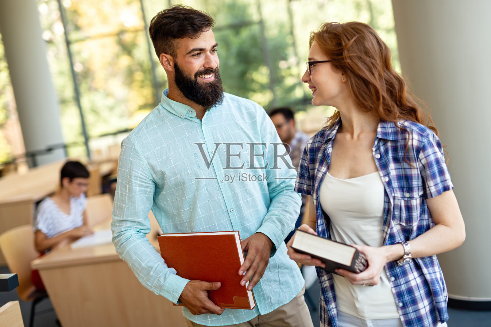 快乐的大学生在图书馆读书。大学里的多种族人群照片摄影图片