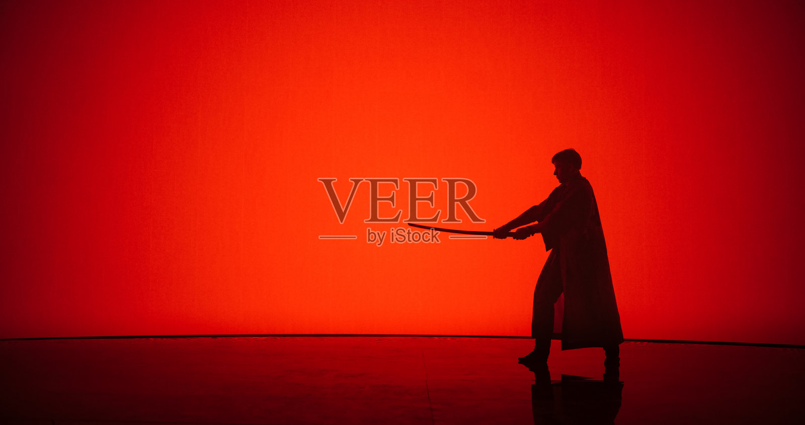 运动员用武士刀或竹剑练习剑道武术。男性做Cosplay，挥舞冷兵器在现代道场风格的数字空间与屏幕上的红色背景照片摄影图片