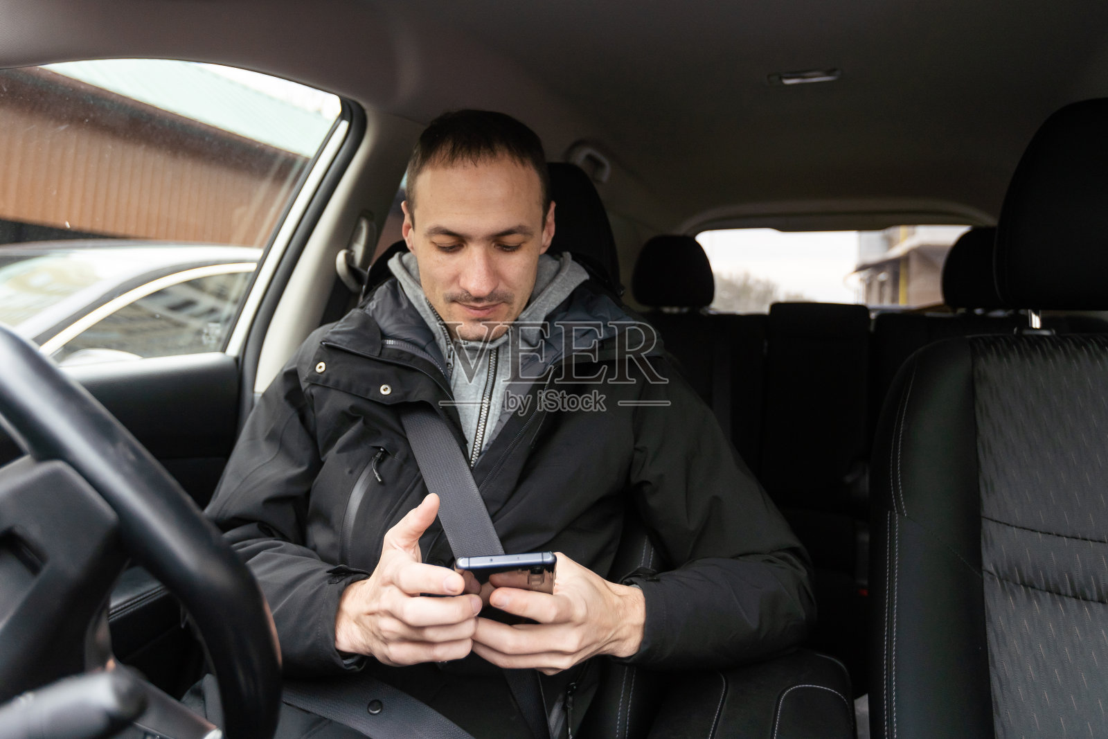 运动中的成功。穿着全套西装的英俊年轻人开着车微笑着照片摄影图片