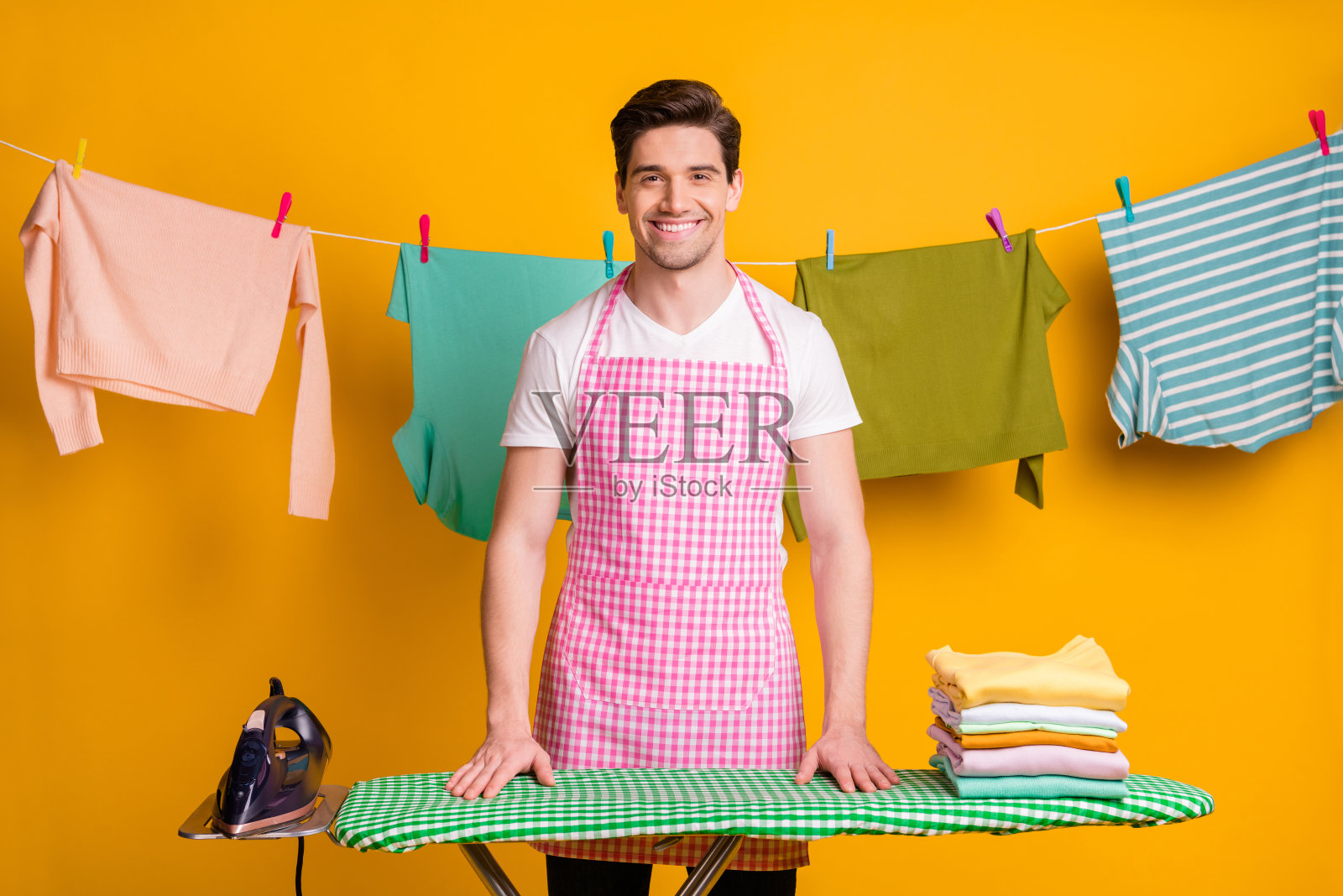 年轻快乐，满意，积极，开朗，微笑的男子的照片完成熨烫孤立的黄色背景照片摄影图片