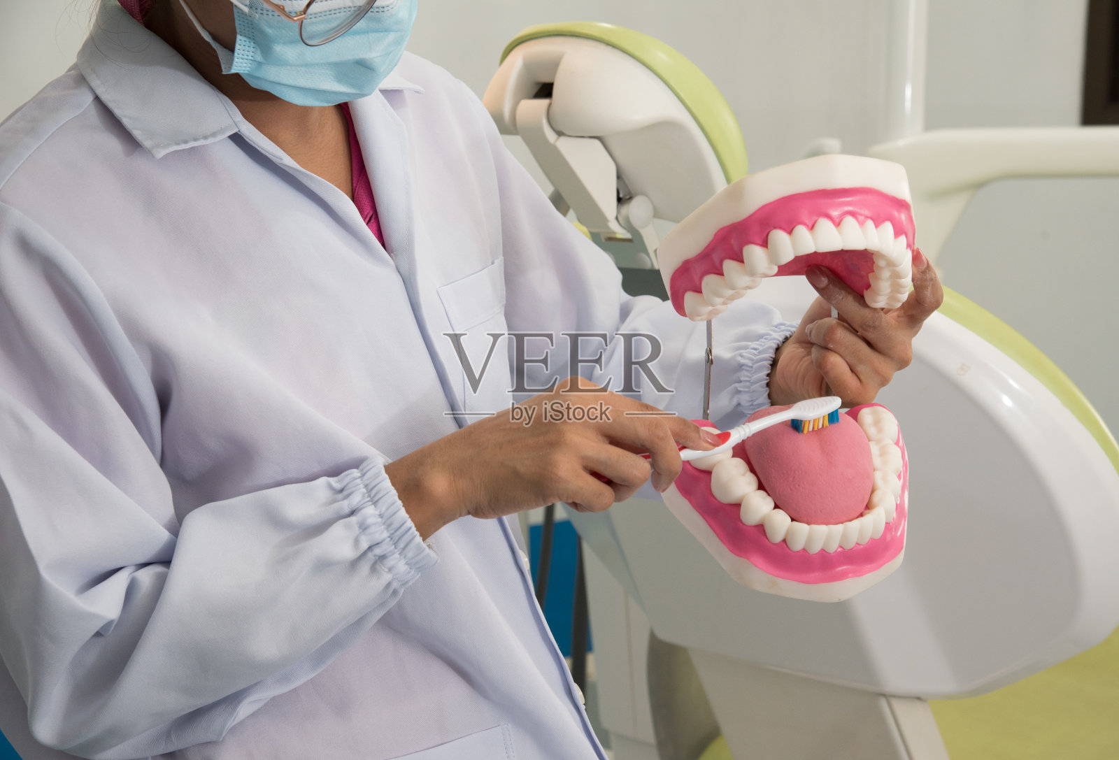牙医一边拿着模型一边在牙科诊所向病人讲解牙科和口腔的治疗方法和治疗方法，病人接受牙科保健咨询。牙科示范照片摄影图片