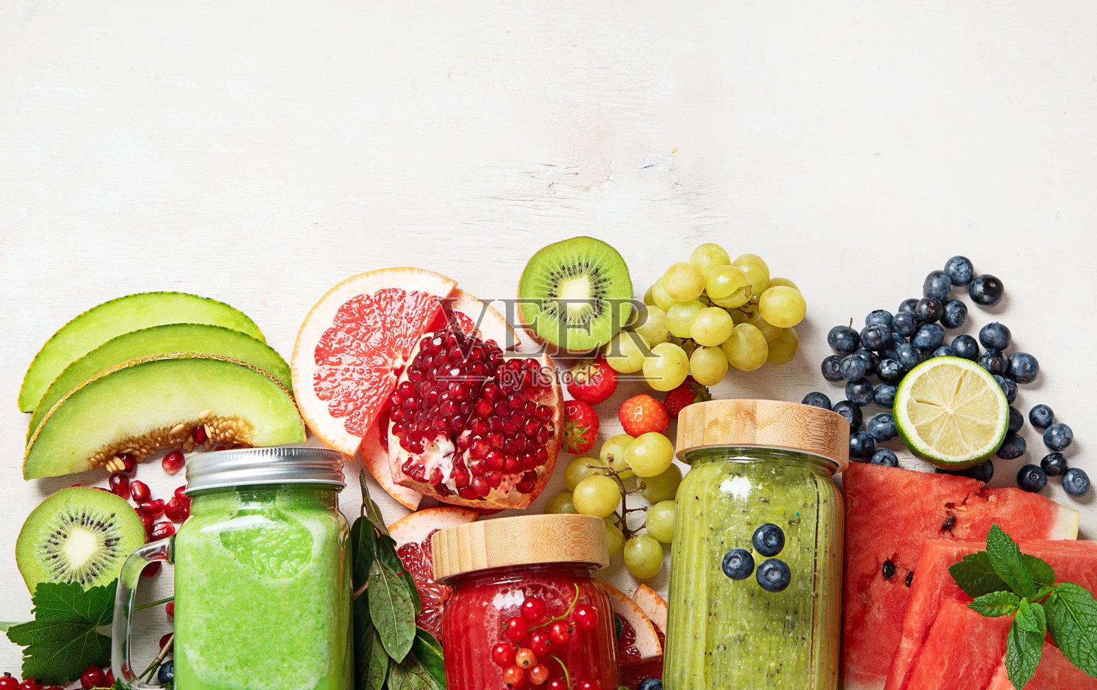 新鲜的水果和蔬菜冰沙或果汁与各种成分在浅色背景。照片摄影图片