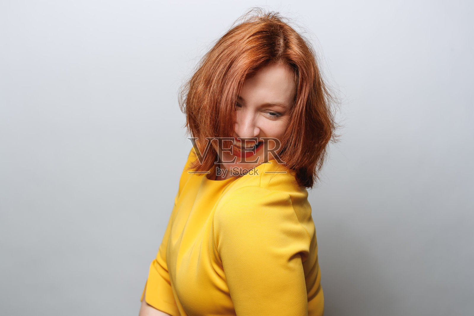 中年妇女的肖像，穿着黄色上衣，快乐地微笑着，回头看照片摄影图片