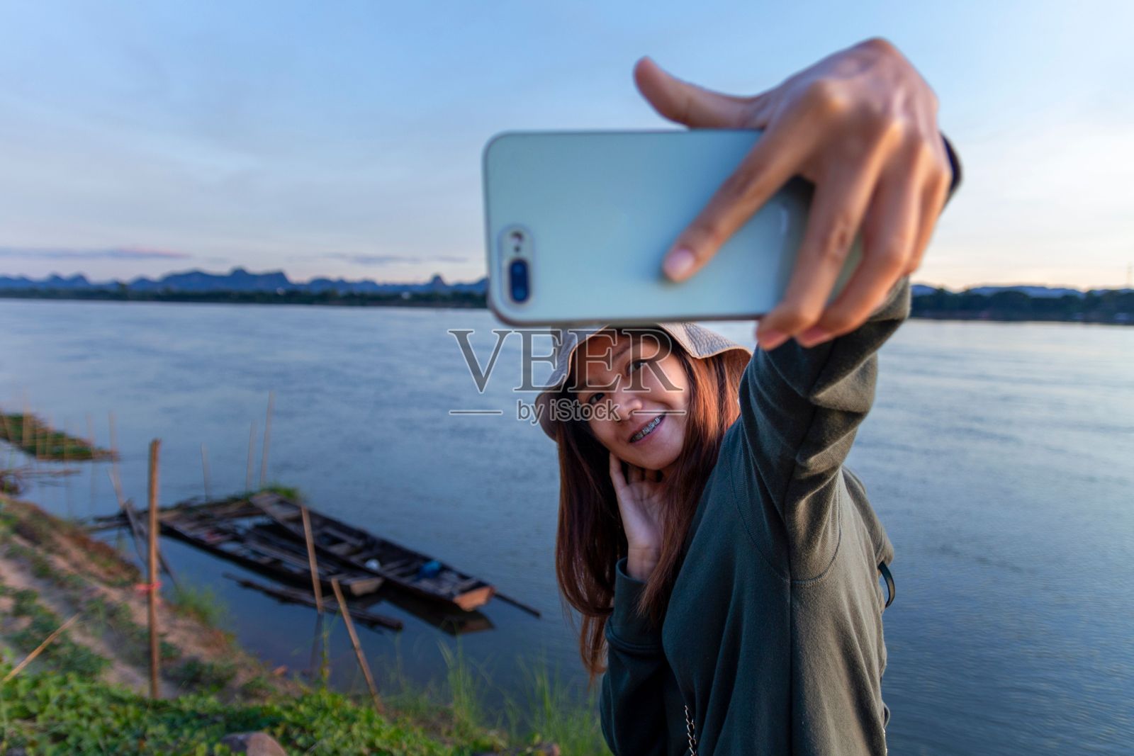 一位女士用白色智能手机拍下了这条河照片摄影图片