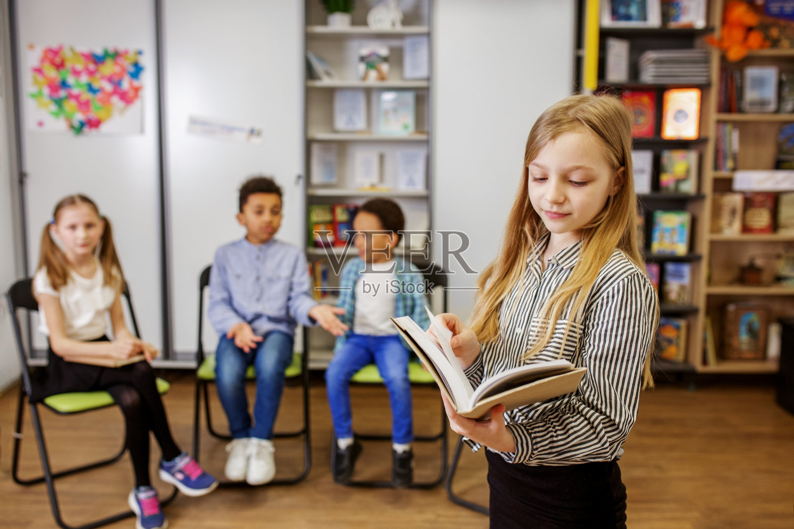 女学生站在教室中间，当着同学和老师的面回答问题照片摄影图片