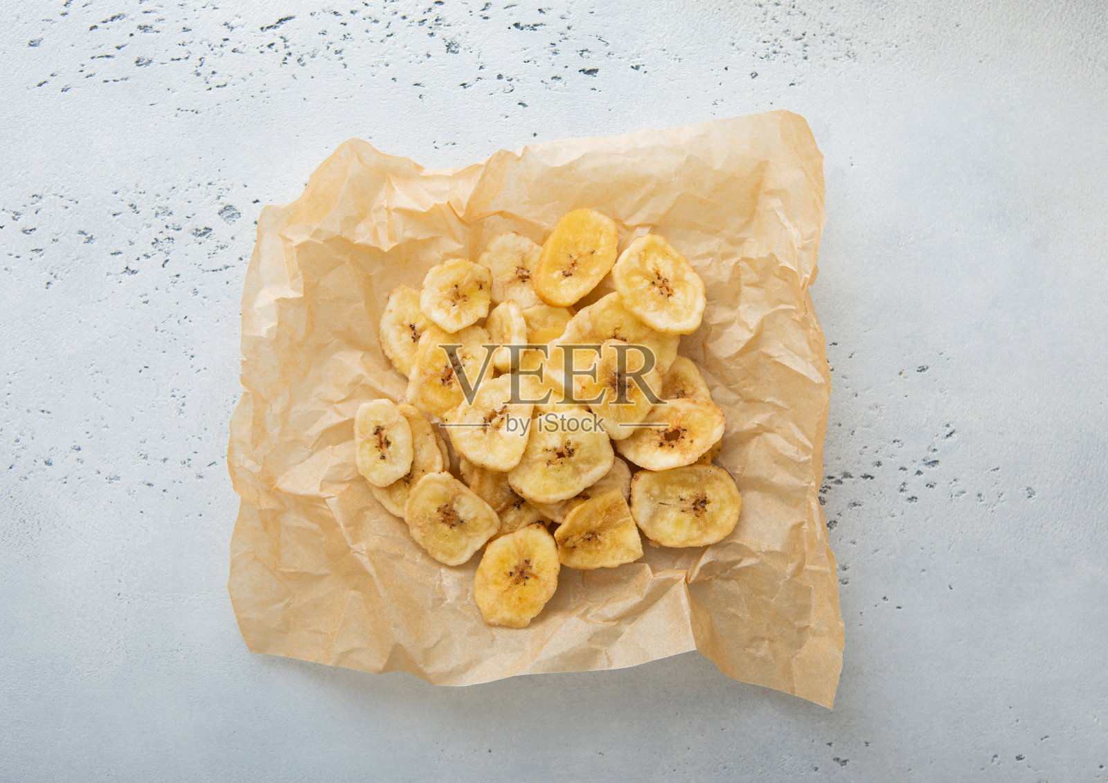 干脆香蕉片在底纸和浅厨房背景。前视图。照片摄影图片