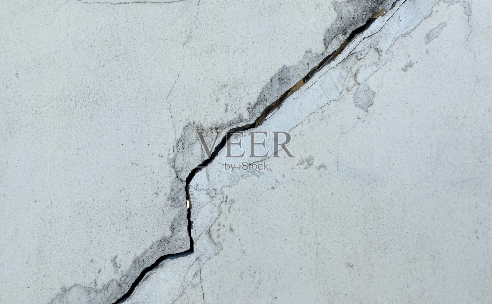 钉在中间有裂缝的混凝土墙上。照片摄影图片