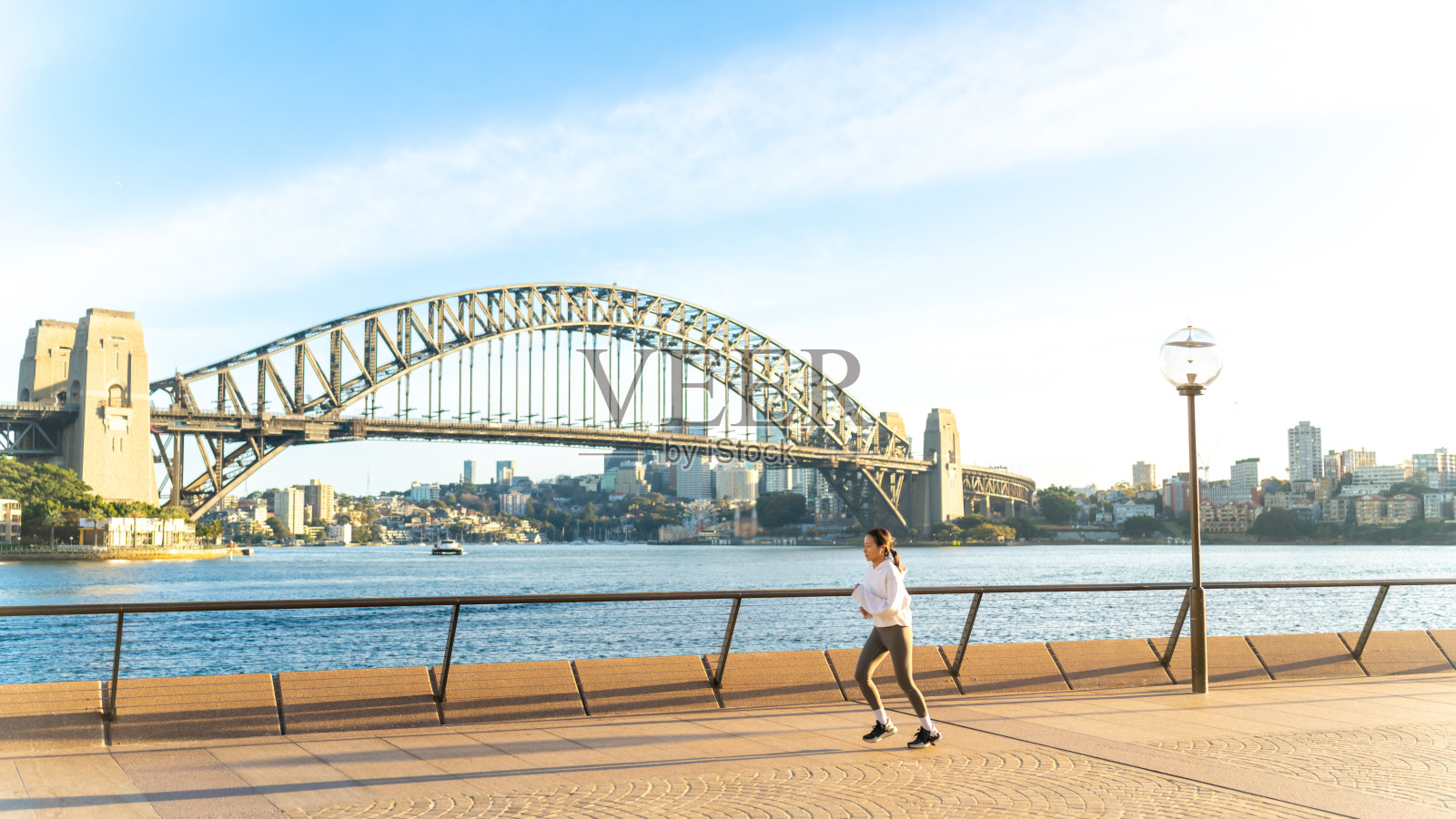 一名亚洲妇女在城市慢跑时戴着耳机听音乐。照片摄影图片