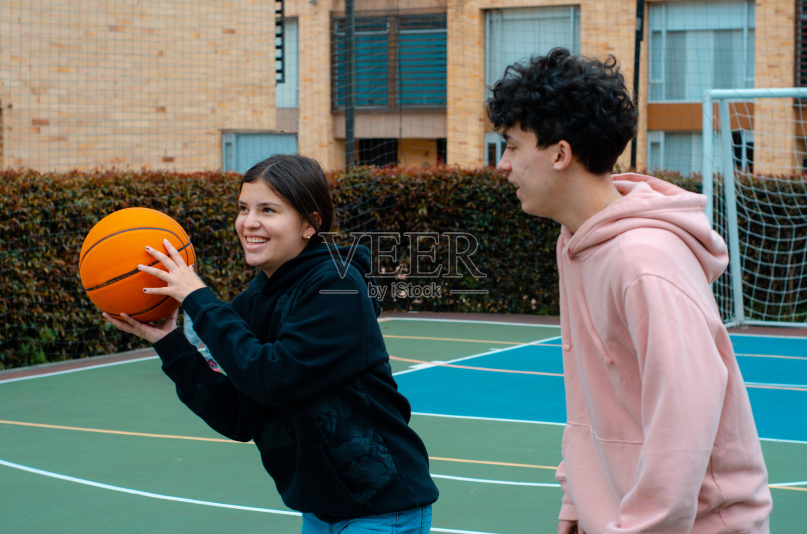 十几岁的男孩和女孩在有复制空间的现代篮球场上打篮球照片摄影图片