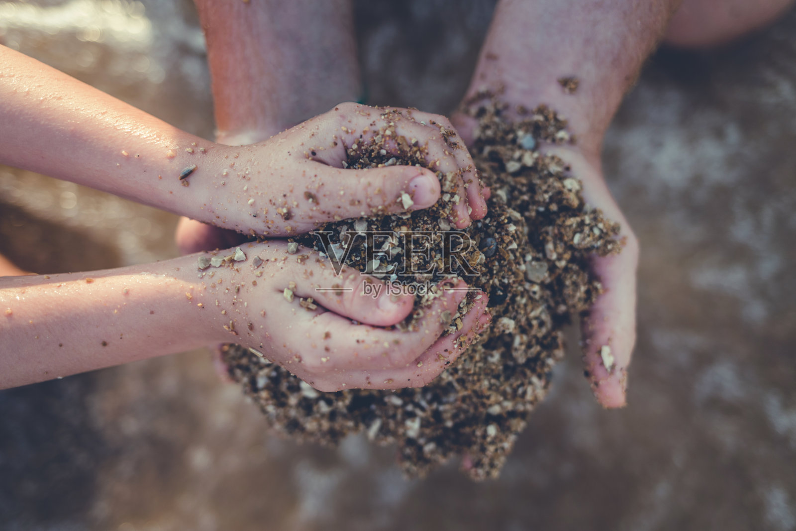 特写两只手在玩沙子。照片摄影图片