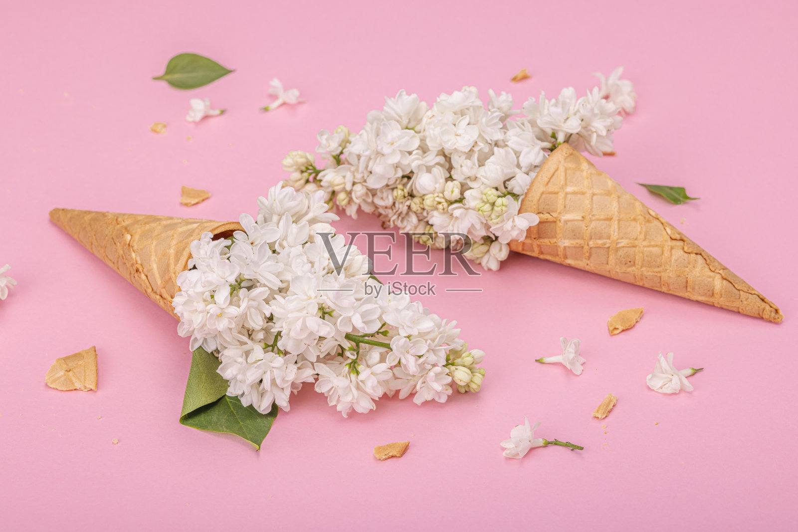 白色丁香花在华夫冰淇淋甜筒粉红色的背景。平铺，春概念照片摄影图片