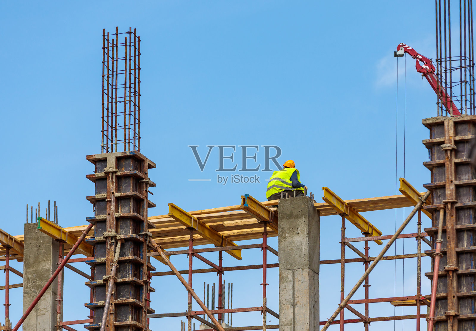 一名男性建筑工人站在高处的钢筋混凝土梁上。照片摄影图片