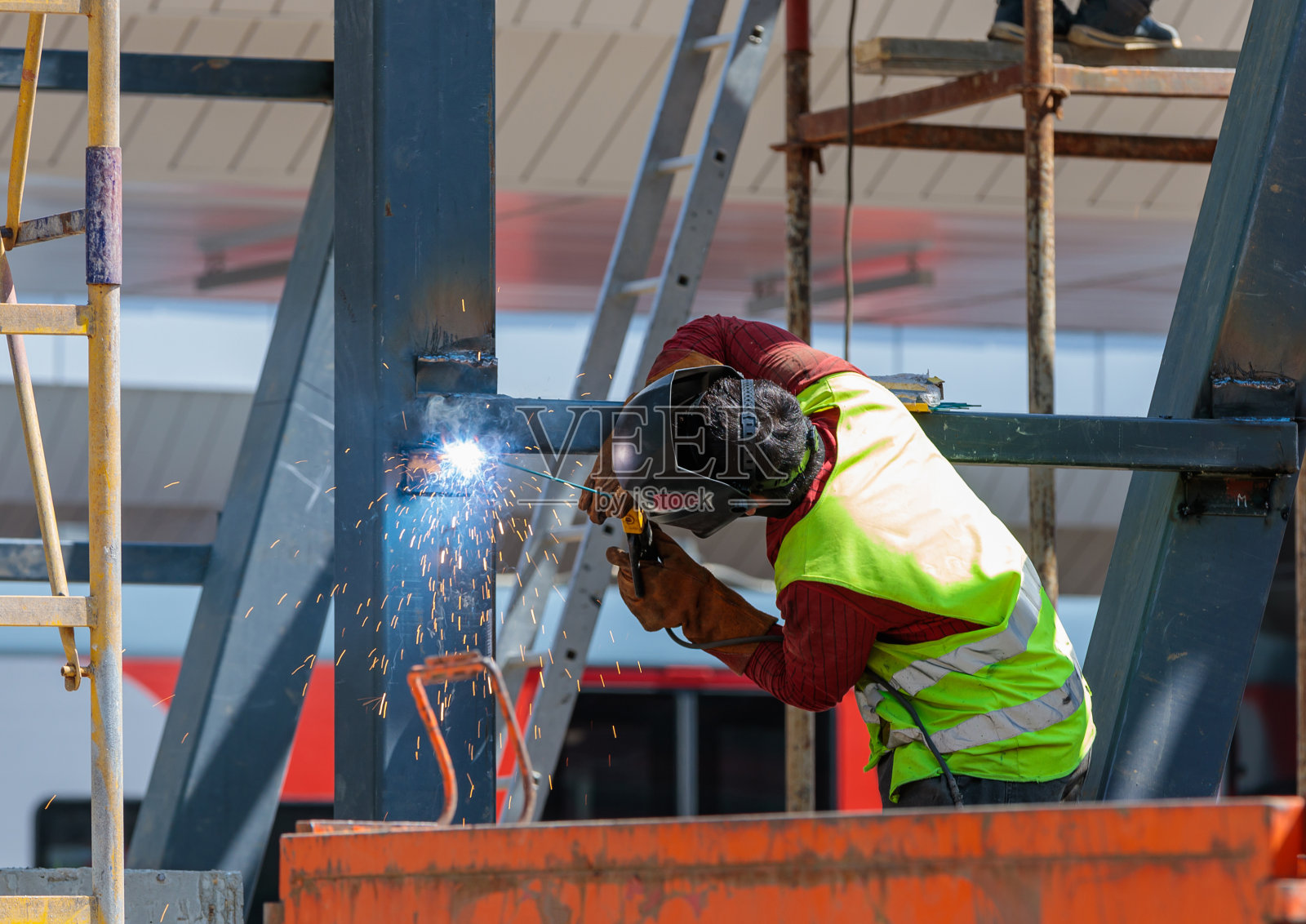 人工焊工用焊机固定铁梁。车站的建设。照片摄影图片