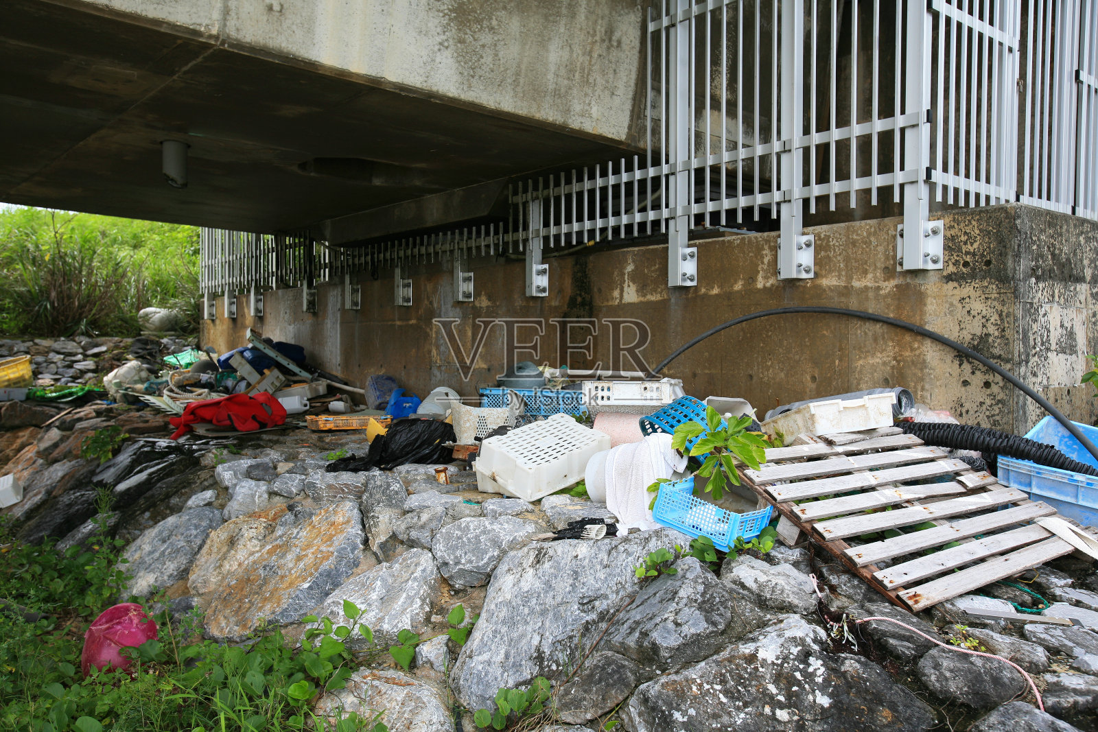 垃圾和渔具堆积在日本冲绳岛的久里桥下。照片摄影图片