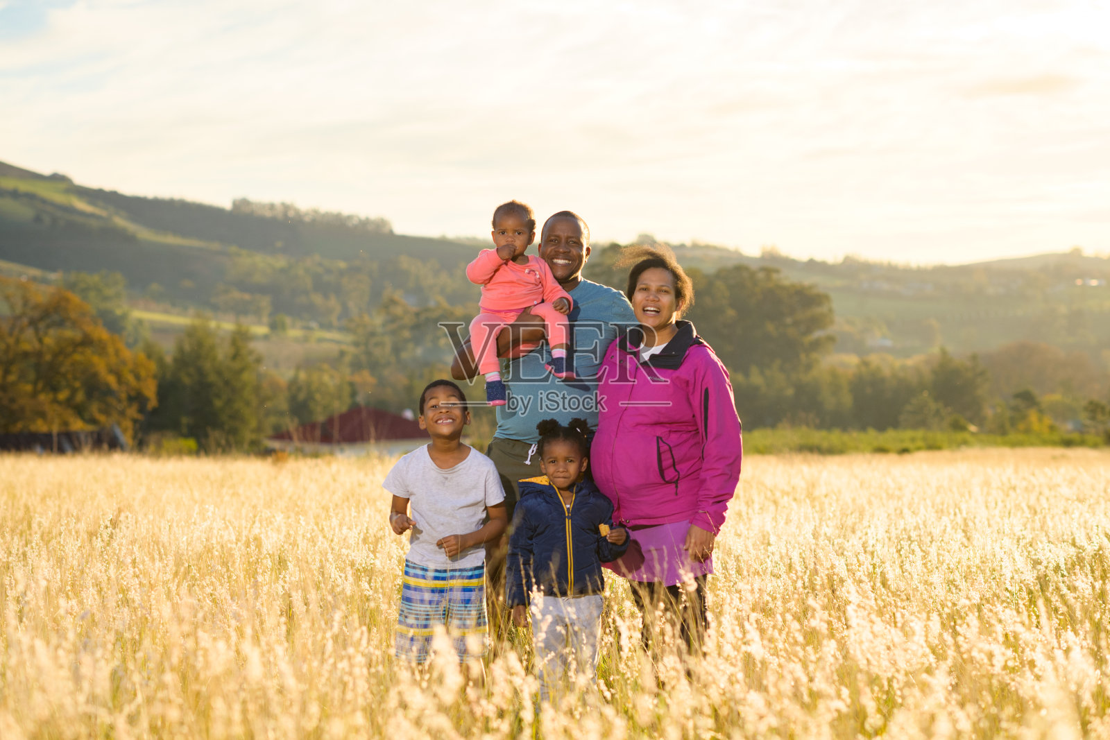 背光户外非洲家庭与怀孕的母亲肖像在草地上日落照片摄影图片