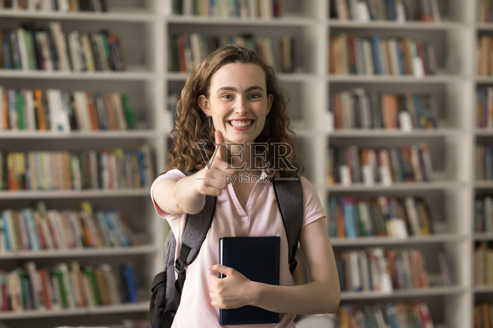 快乐的美丽的女大学生用喜欢的手势照片摄影图片