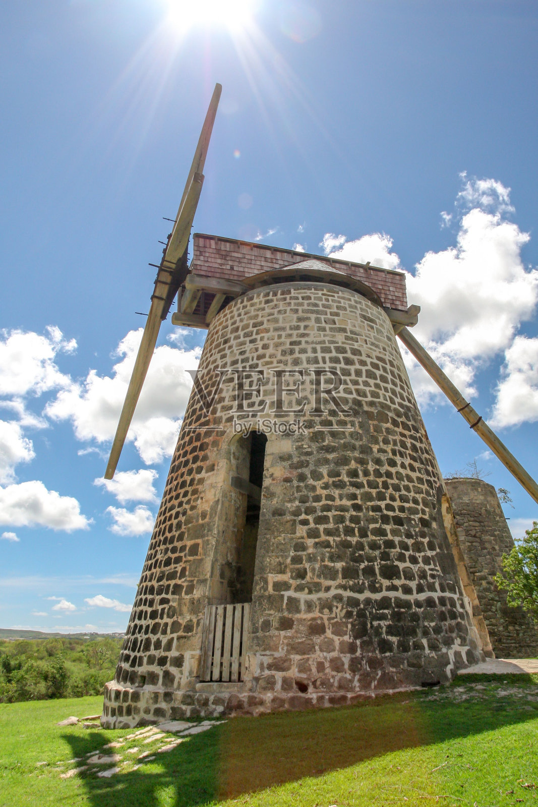 一个美丽的，古老的石头风车垂直视图设置在一个郁郁葱葱的绿色田野照片摄影图片