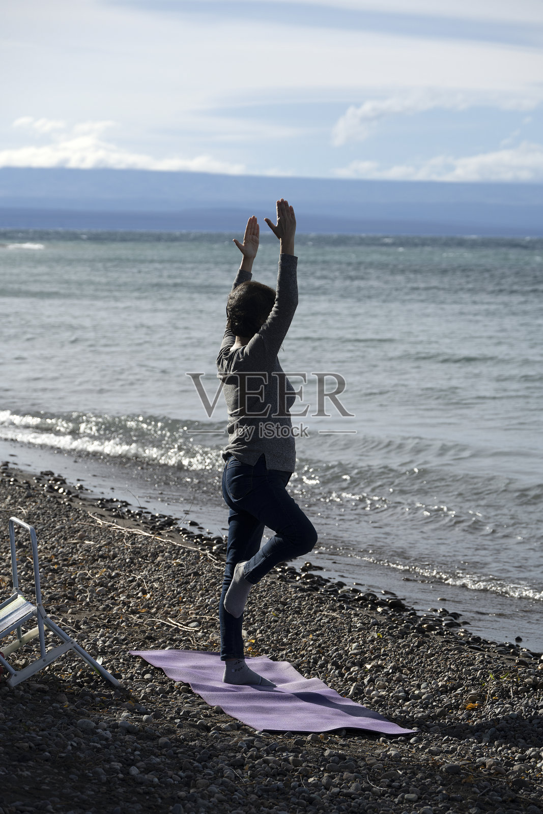 一位老妇人在湖边独自练习瑜伽。照片摄影图片