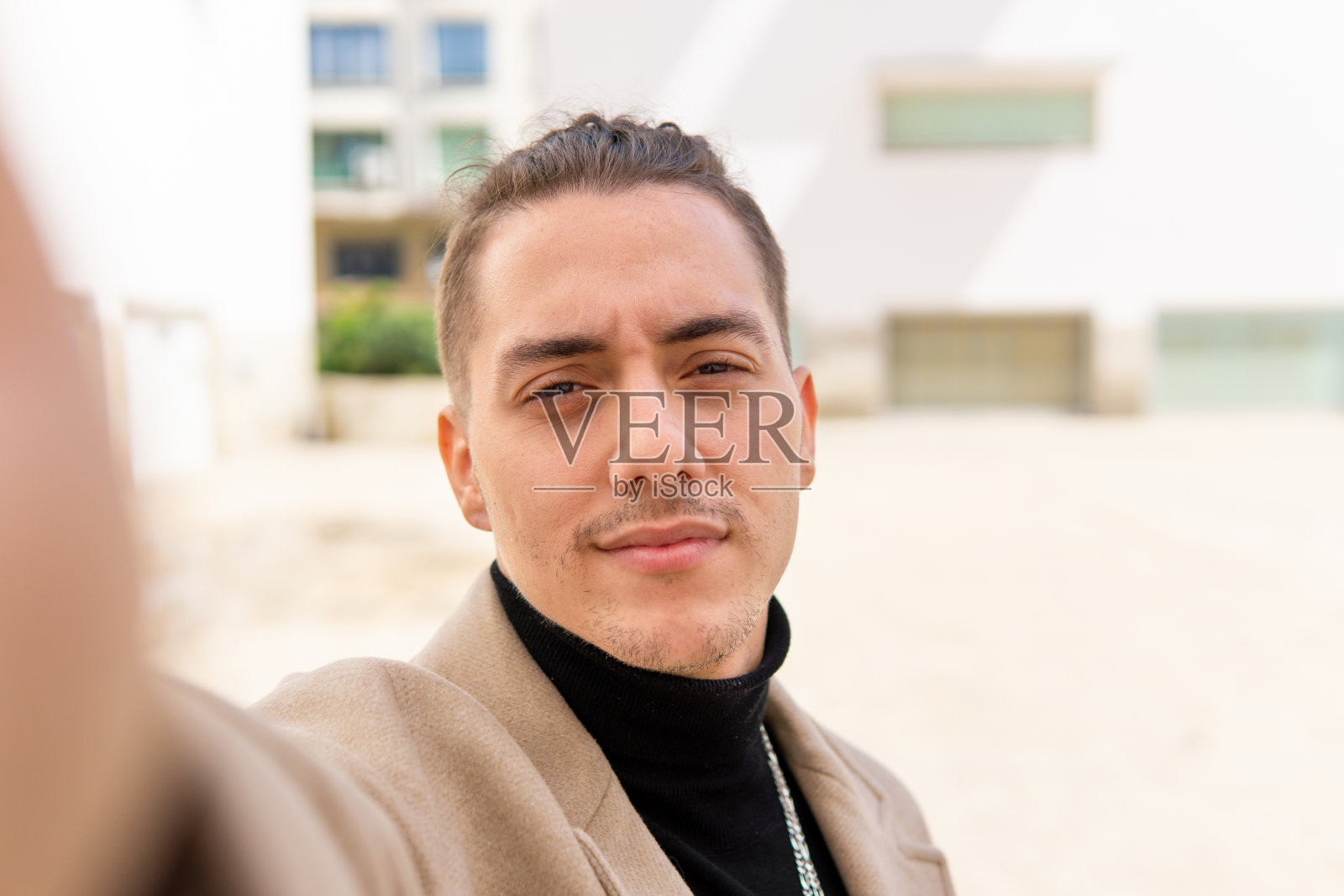 一名年轻的混血男子在城市里用智能手机自拍照片摄影图片