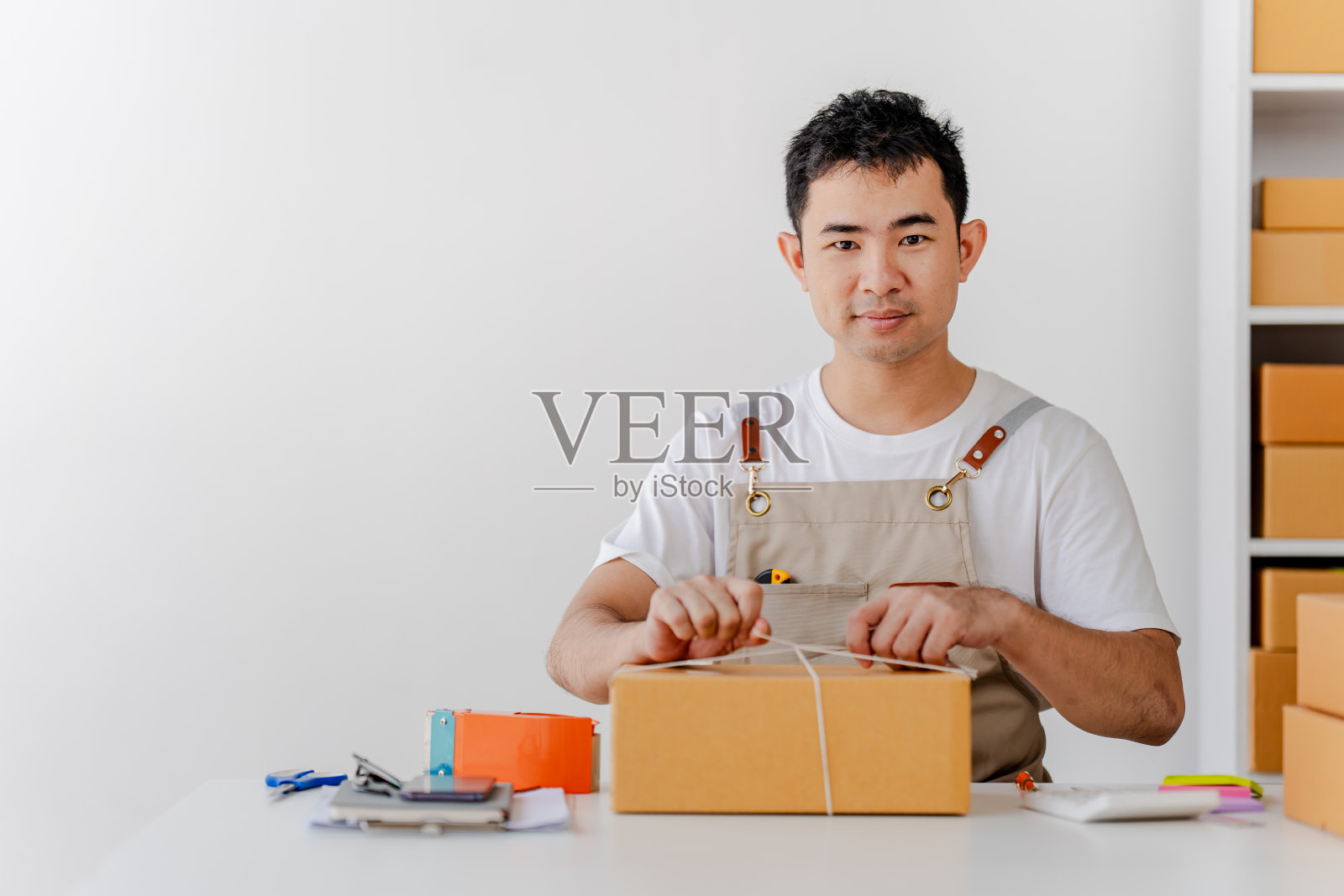 中小企业创业小男，在工作中检查包裹，自由职业者，推销员，检查生产订单，包装产品交付给客户，中小企业概念照片摄影图片