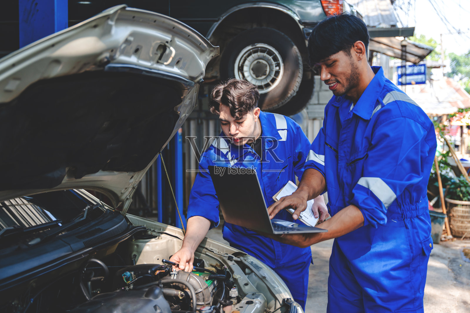 机修工为客户检查和维护发动机。这是一款将维修机器、汽车服务和维护清单写在剪贴板上的应用程序。照片摄影图片