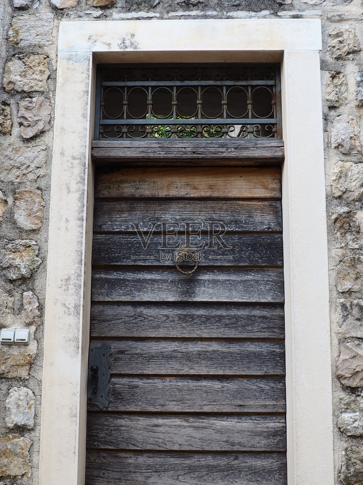 门环是房子前门上的固定装置。它是由金属制成并具有圆环的形式，是门环的金属部分被敲固定在墙上。黑山Herceg Novi。照片摄影图片