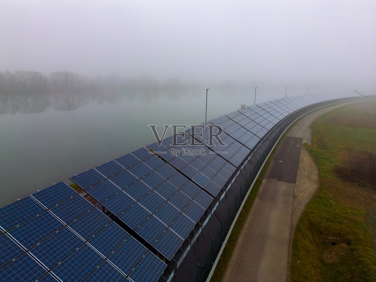 晴朗的天空下，乡村公路旁一排排的太阳能电池板照片摄影图片
