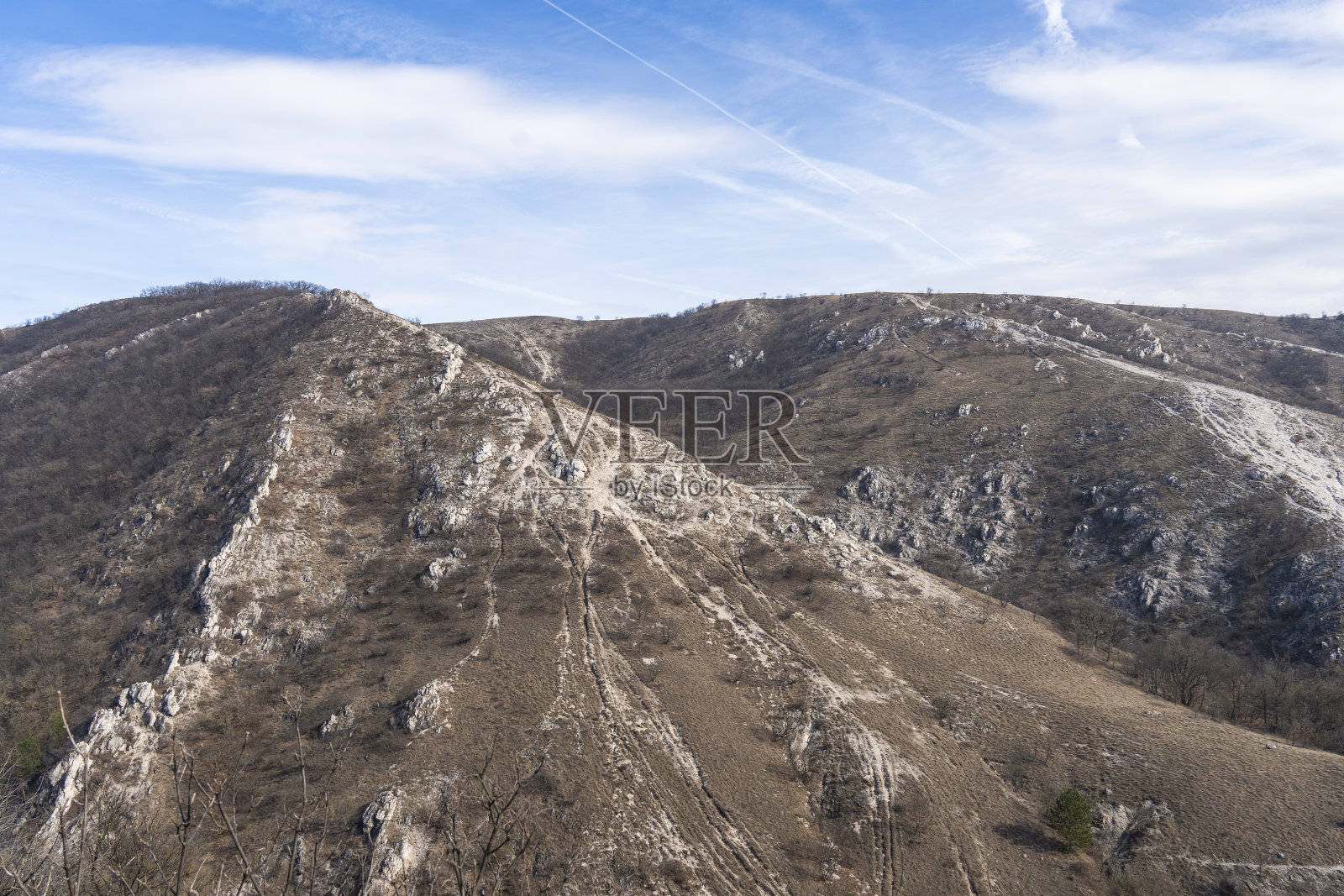 冬日阳光下死气沉沉的褐色岩石山丘照片摄影图片