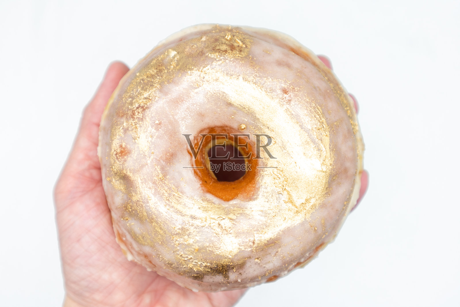 闪亮的大黄金甜甜圈手握照片摄影图片