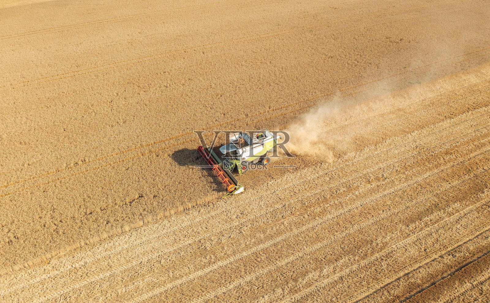 无人机航拍图:日落时分，联合收割机在麦田里劳作。照片摄影图片