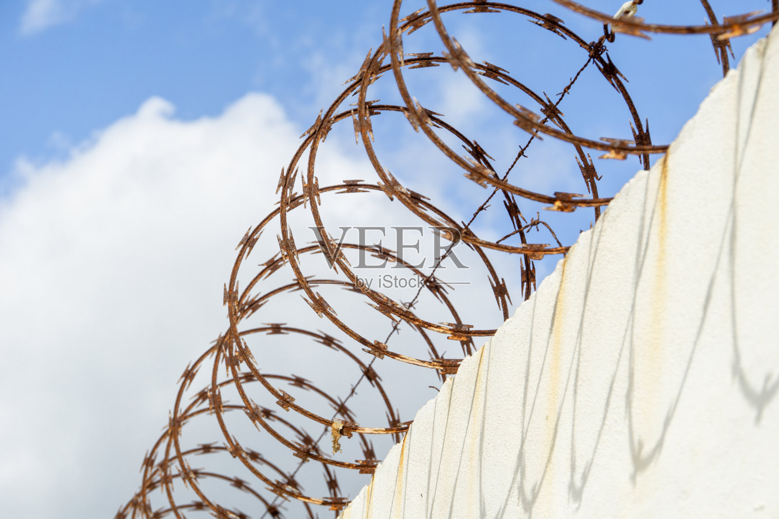 带刺的铁丝网映衬着多云的天空。带刺铁丝的监狱栅栏。剥夺自由的概念。照片摄影图片