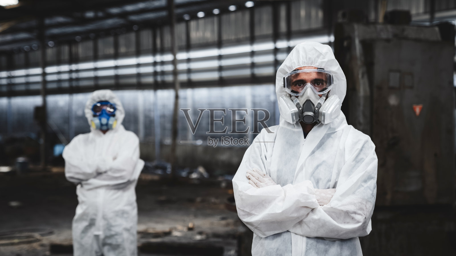 在老工厂里，工人们穿着防护服检查被化学污染的油。防止危害和污染。照片摄影图片