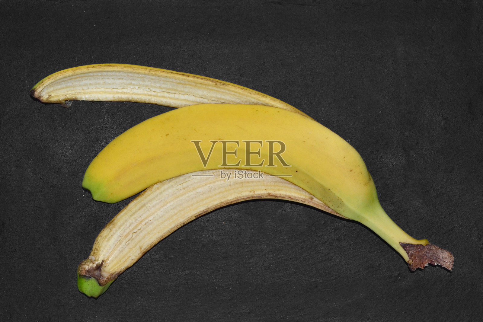 一个香蕉皮躺在黑色的背景上照片摄影图片