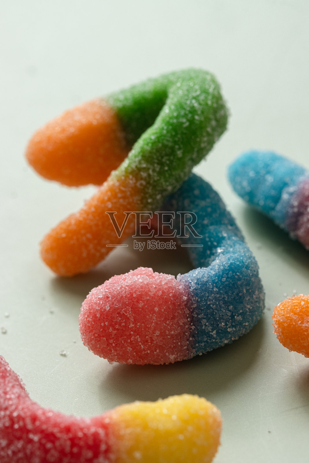 五颜六色的软糖蠕虫。前视图。浅绿色平滑的背景。近距离照片摄影图片