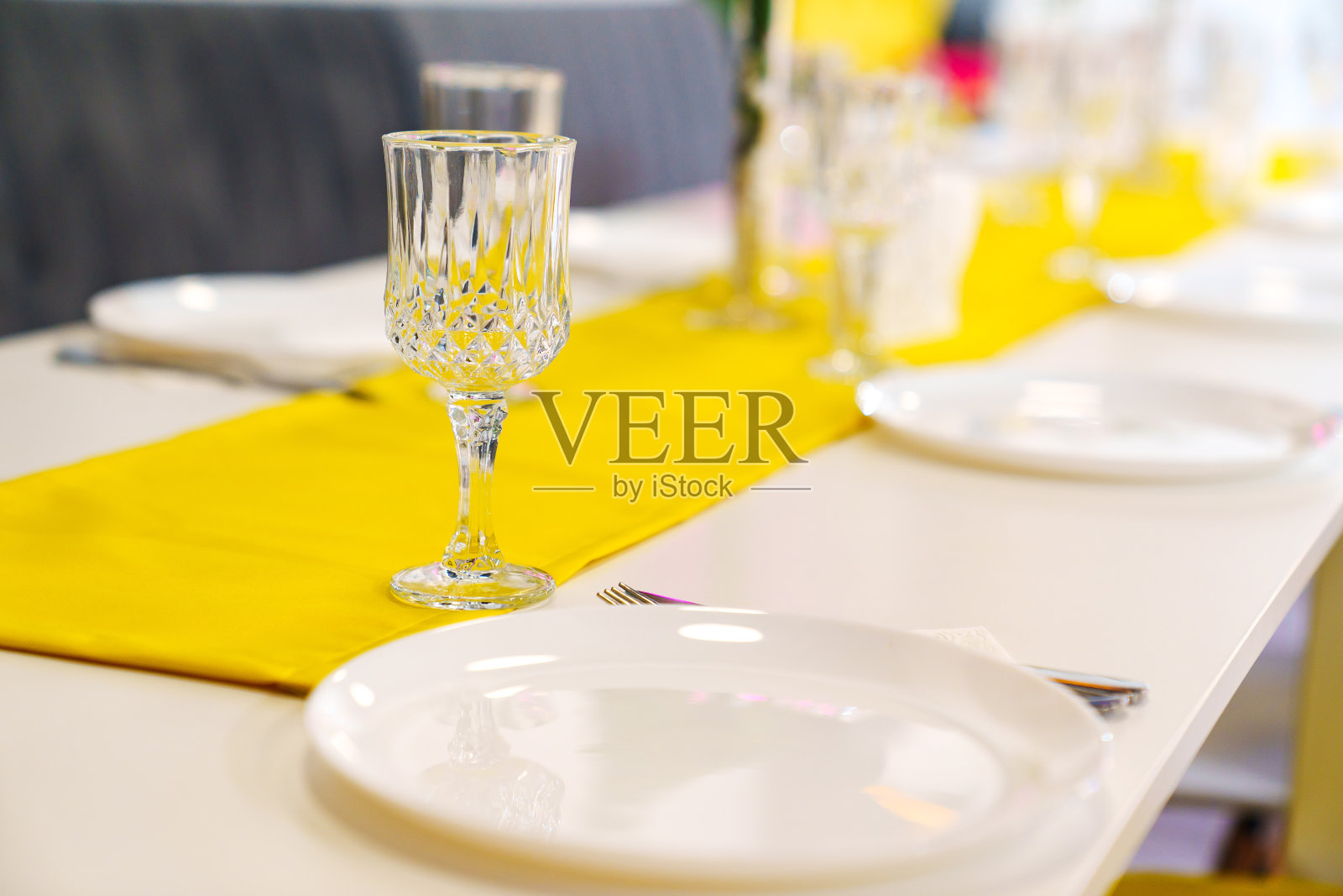 一张铺着黄色桌布的桌子，上面放着玻璃杯和盘子。照片摄影图片