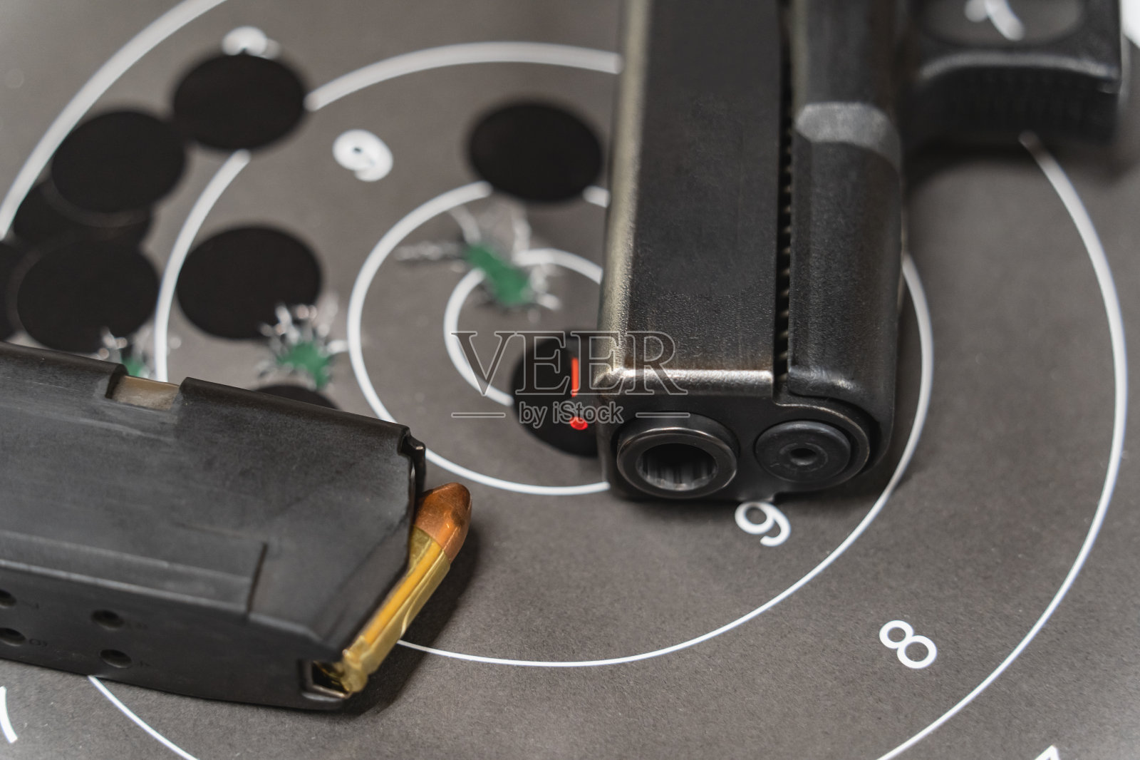 一支手枪，一个装有子弹的弹匣和一个中间有弹孔的靶标，特写照片。照片摄影图片