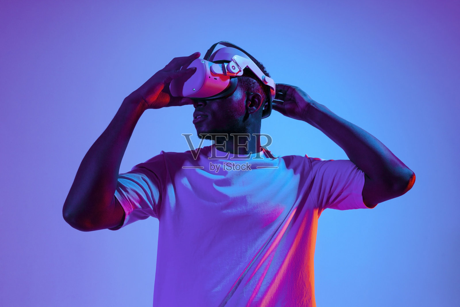一个非裔美国人在霓虹灯下戴着虚拟现实眼镜，这家伙使用虚拟现实设备照片摄影图片