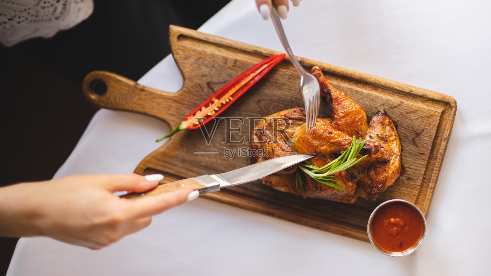 美味的鸡腿配上烧烤酱和辣椒放在木板上。刀叉。食品摄影。照片摄影图片