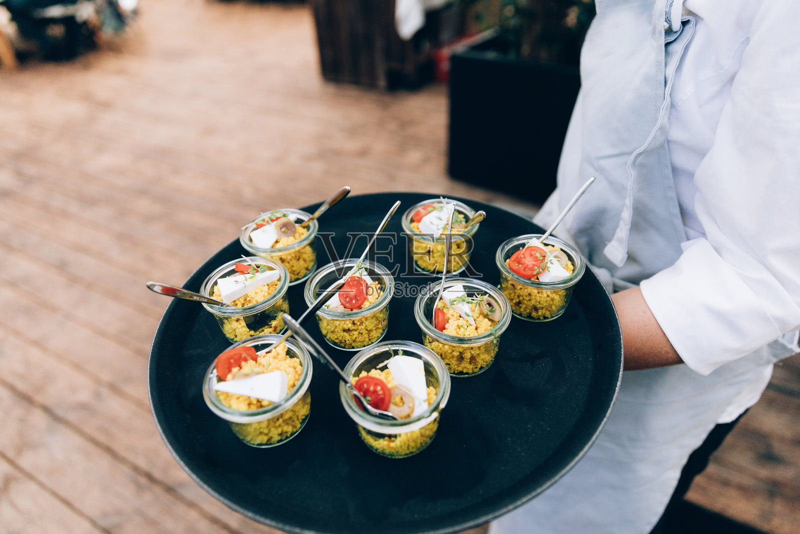 女服务员在餐厅里为客人端上蒸粗麦粉沙拉。照片摄影图片