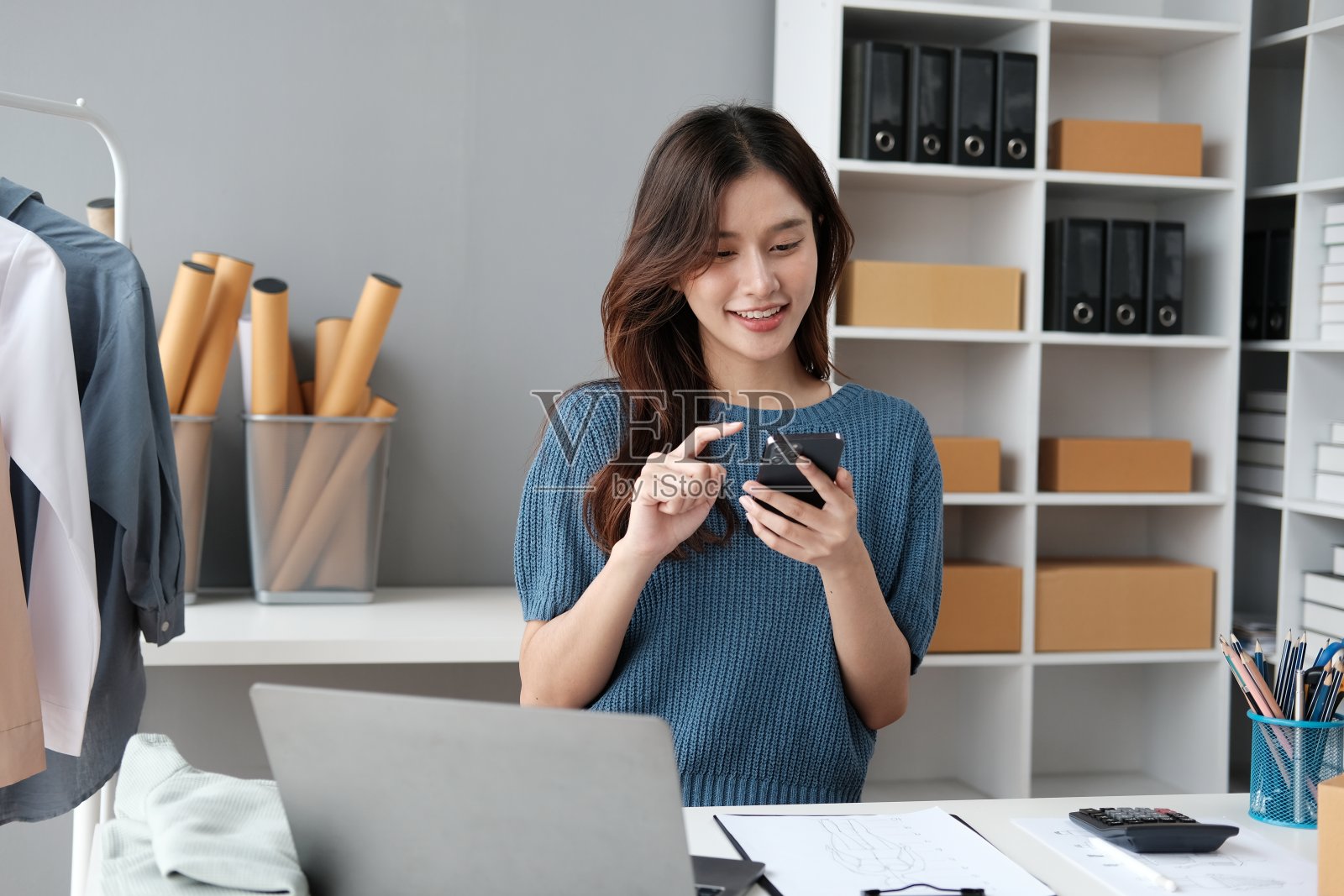 中小企业主在工作中使用笔记本电脑。用包裹纸盒投递给客户进行网上销售。照片摄影图片