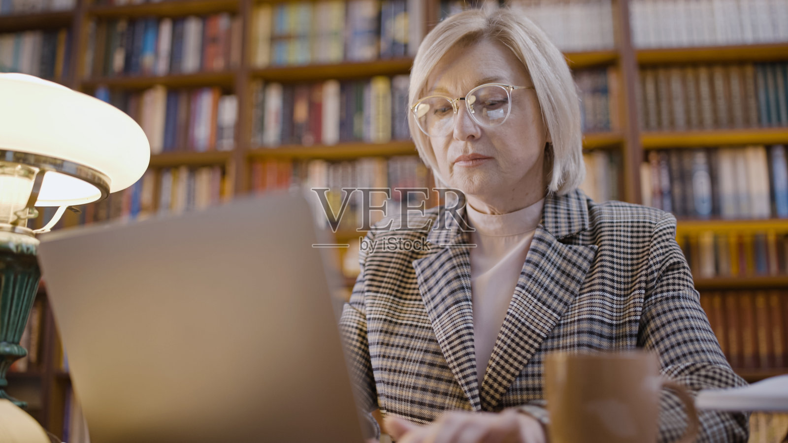 50多岁的女人在笔记本电脑上打字，加班，自由职业者，远程工作者照片摄影图片