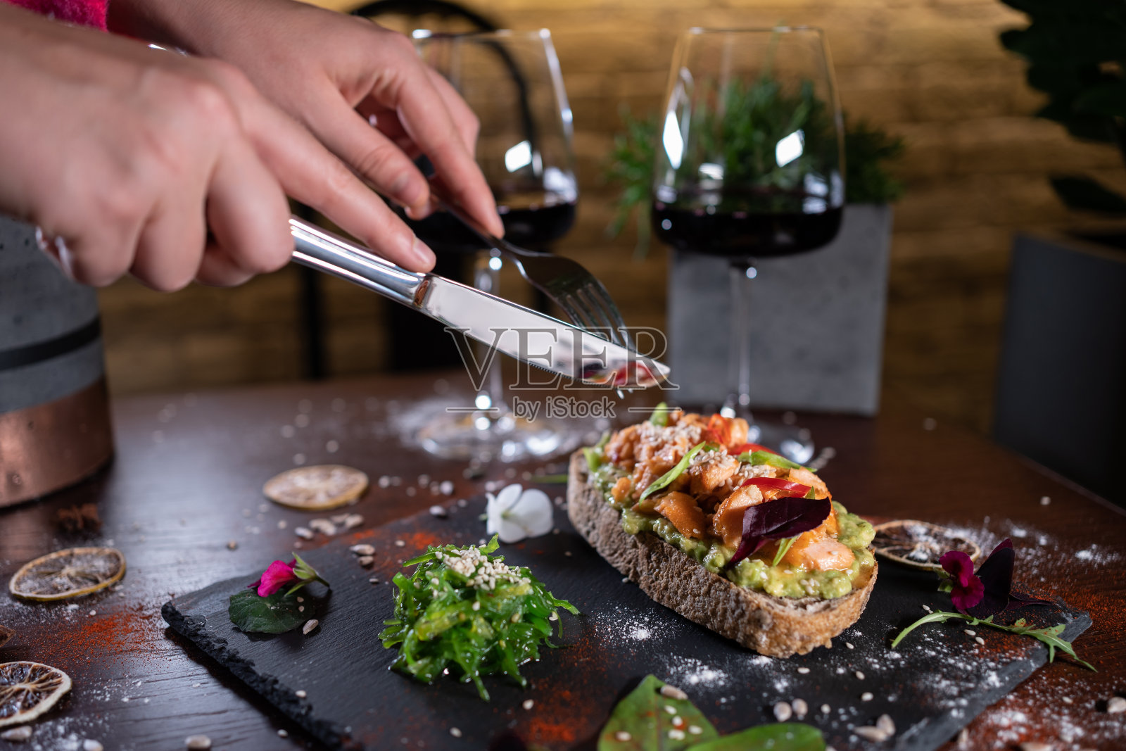 人吃新鲜的三明治配牛油果、红鲑鱼、炸鱼、海带、酒照片摄影图片