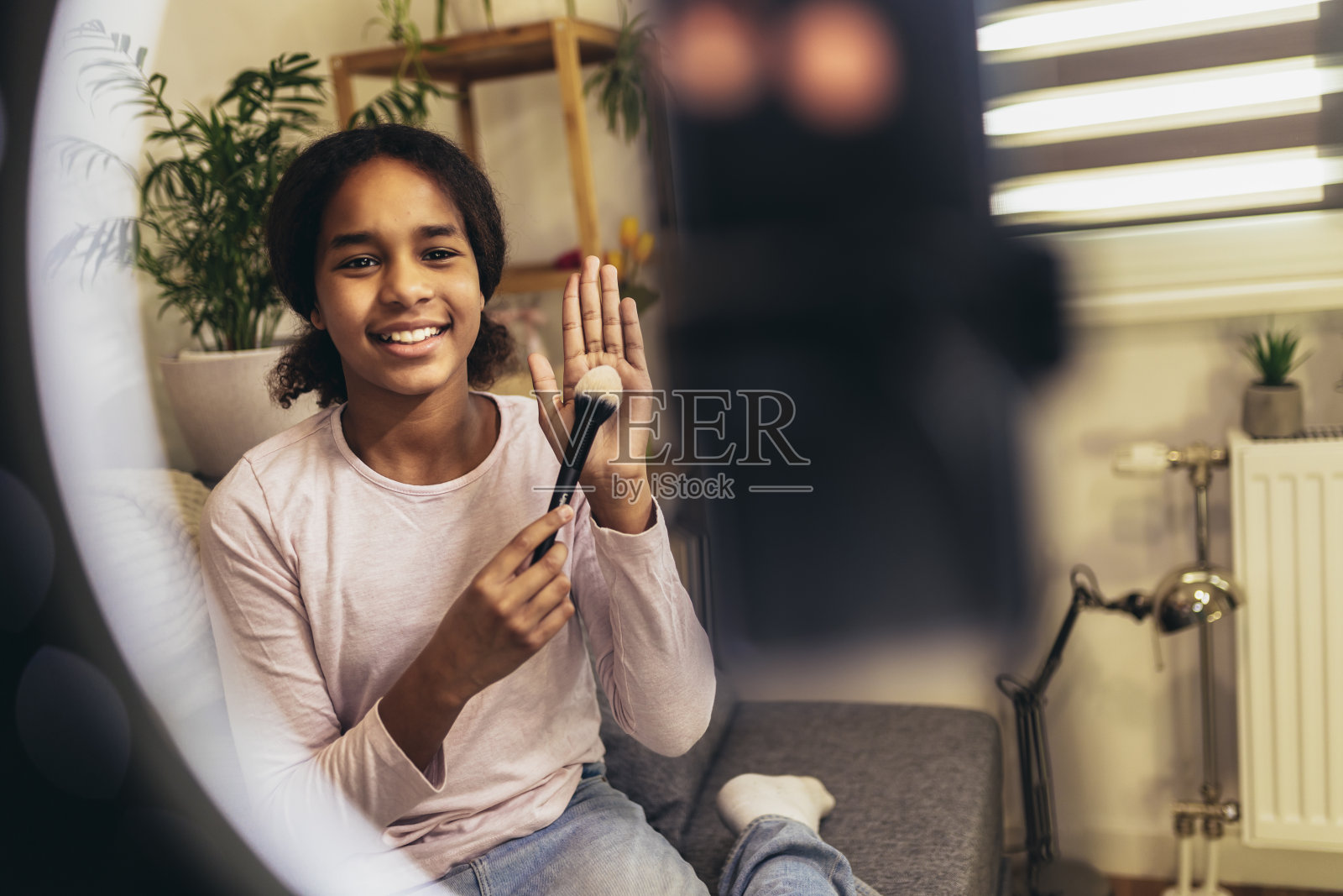 十几岁的女孩在家里用智能手机制作视频博客。美容、化妆照片摄影图片