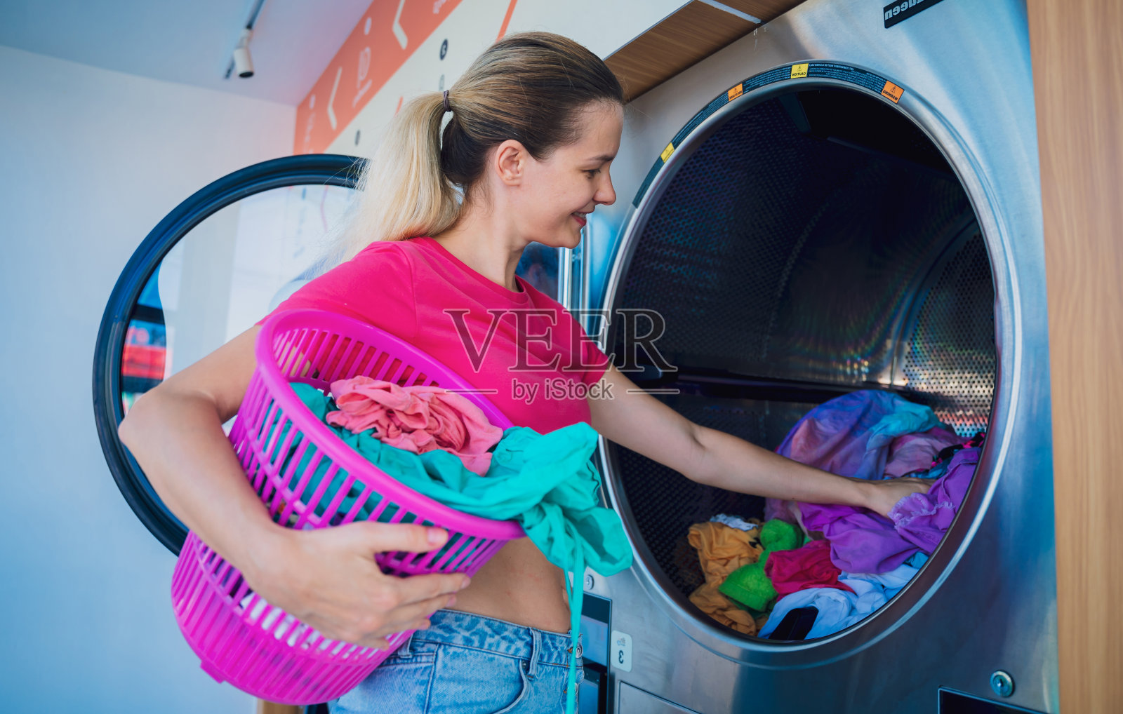 年轻漂亮的女人在洗衣房洗衣服和烘干衣服照片摄影图片