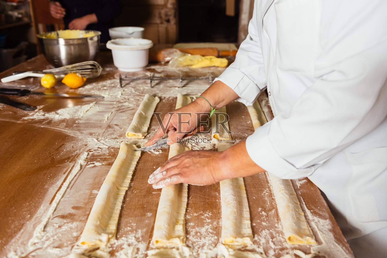 一个面目全非的人站在桌子上准备奶油馅的油酥卷照片摄影图片