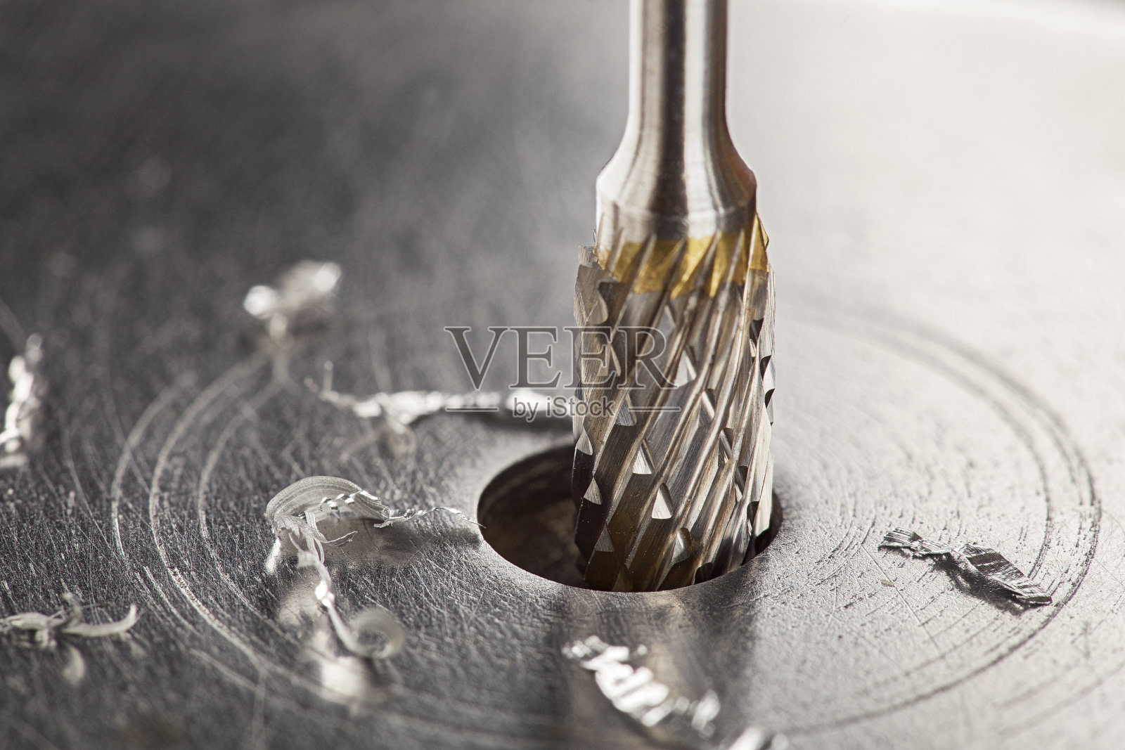 铣刀和钻头在钢坯上形成孔槽。钳工的工作。照片摄影图片