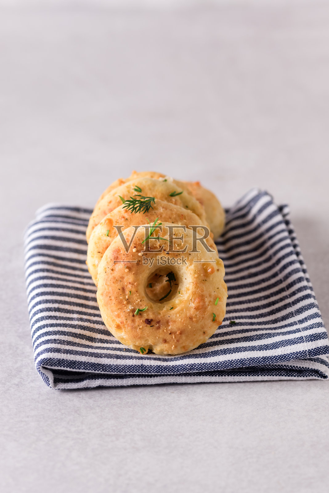 新鲜烘焙的自制百吉饼，奶酪和香草，浅灰色的背景照片摄影图片