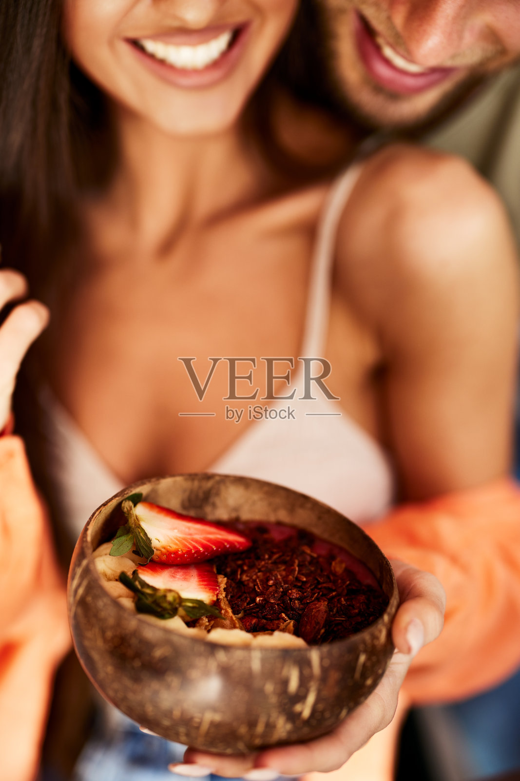 一男一女抱着一碗健康的水果。选择性地关注水果。照片摄影图片